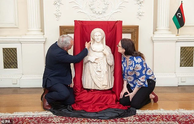 British Museum staff Peter John Higgs (left), the Head of the Greece and Rome Department and Hannah Boulton (right) were pictured with the statue at the Libyan Embassy in central London