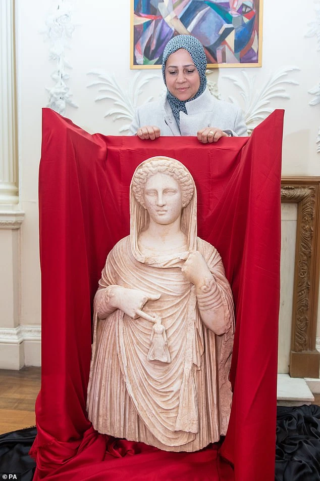 Libyan Embassy First Secretary Enas Kaal stands behind the statue at the Libyan Embassy in London, where she will remain until she returns to Libya in the coming weeks.