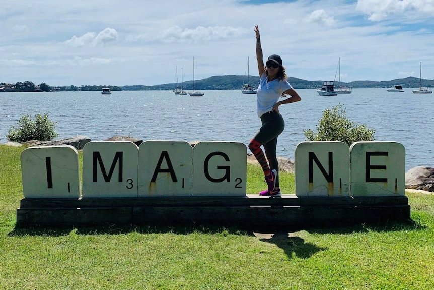 A woman poses with a Scrabble sculpture.