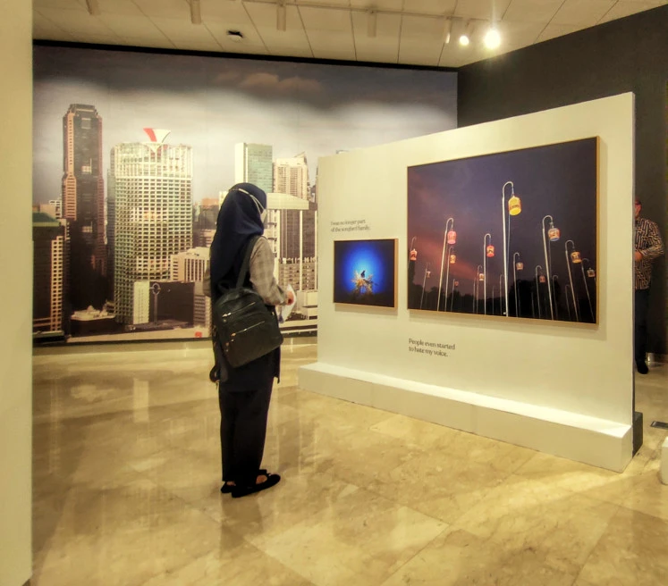 In Cage: A visitor to the exhibit looks at a photo of Javan Mynahs in cages.  (JP/Sylviana Hamdani)
