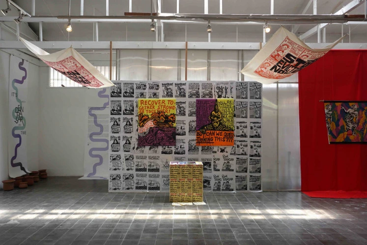 Eye-catching: “Bukan Recover Together, Bukan Stronger Together” 2022 by Gilang Propag, an installation comprising acrylic and gouache paintings on canvas, wheat paste posters on the wall, screen printing on fabric and pages of Zine.  Organized by Wicitra Pradnyaratih.  (Courtesy of CushCush Gallery)