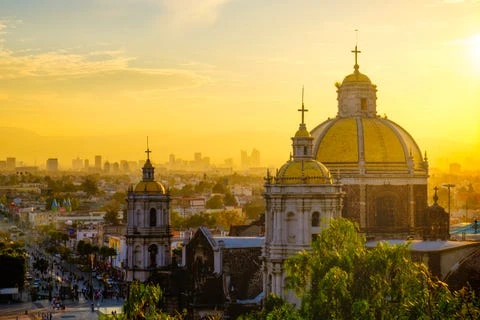 panoramic view of basilica de guadalupe with mexico city skyline at sunset, mexico
